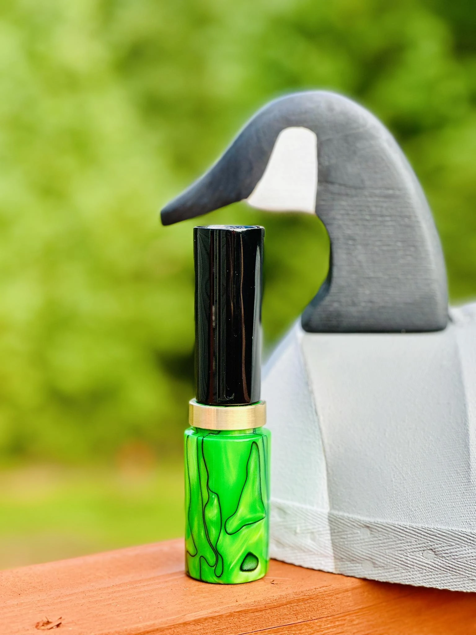 Two light wood hand turned game calls on a dark tabletop.