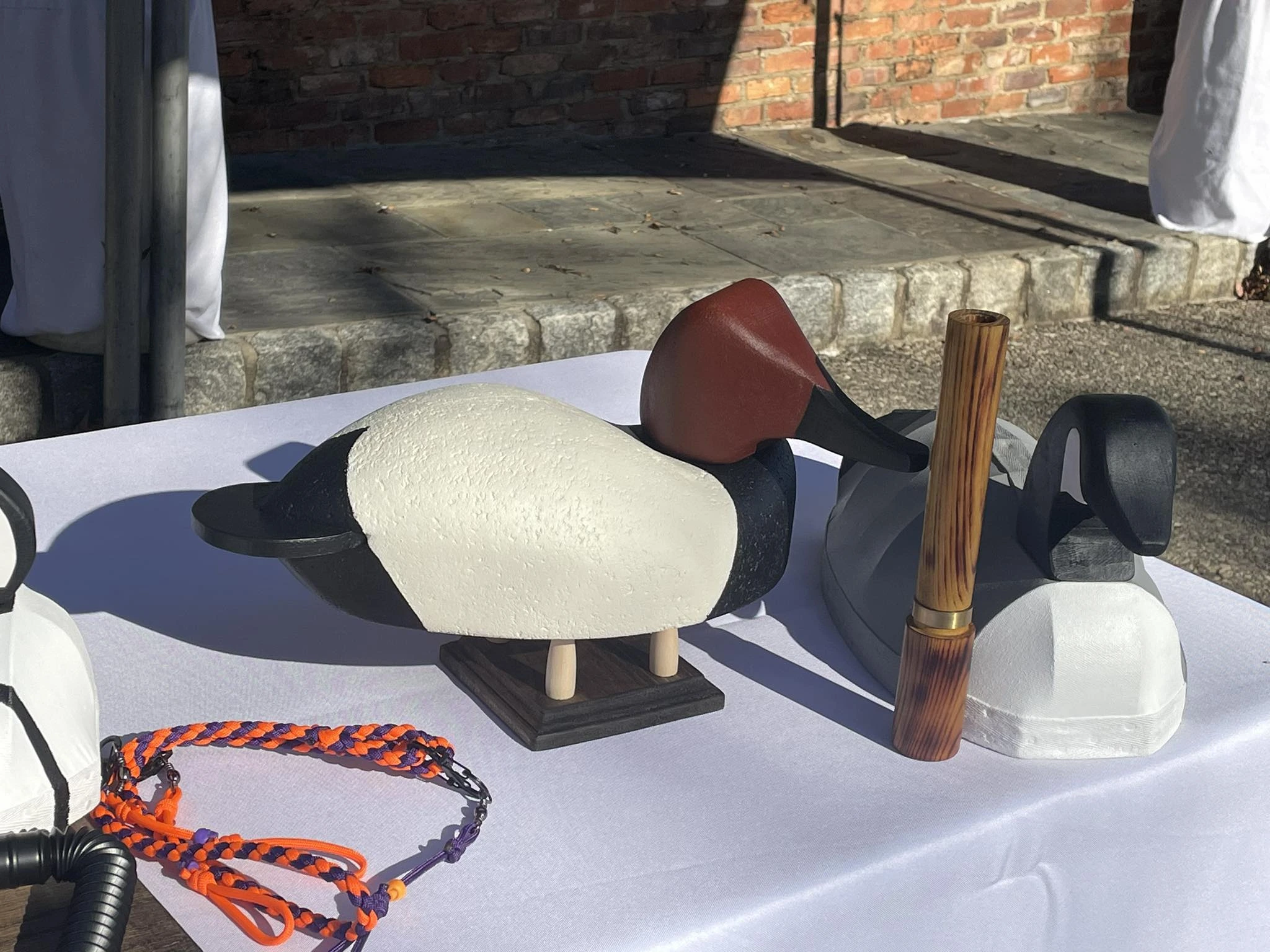 Canvas decoys and a tall hand turned game call displayed on a table.
