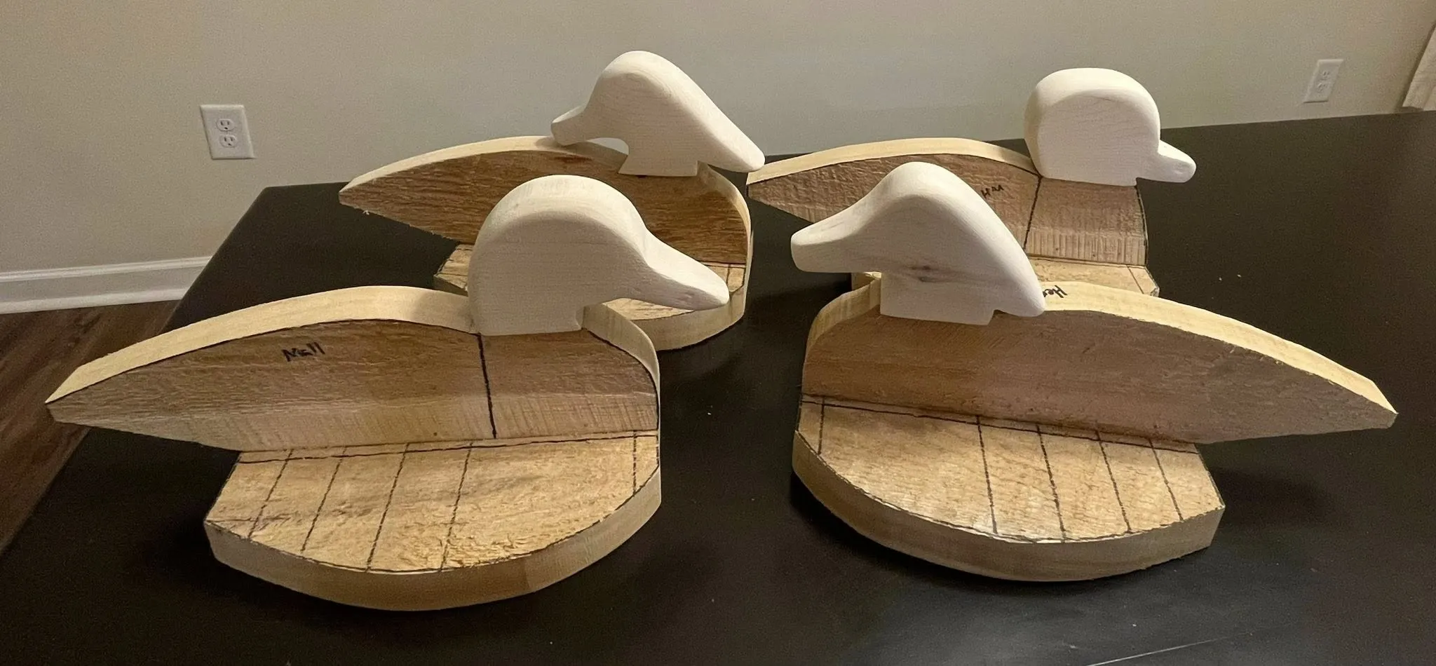 Unfinished carved decoy forms arranged on a work table.