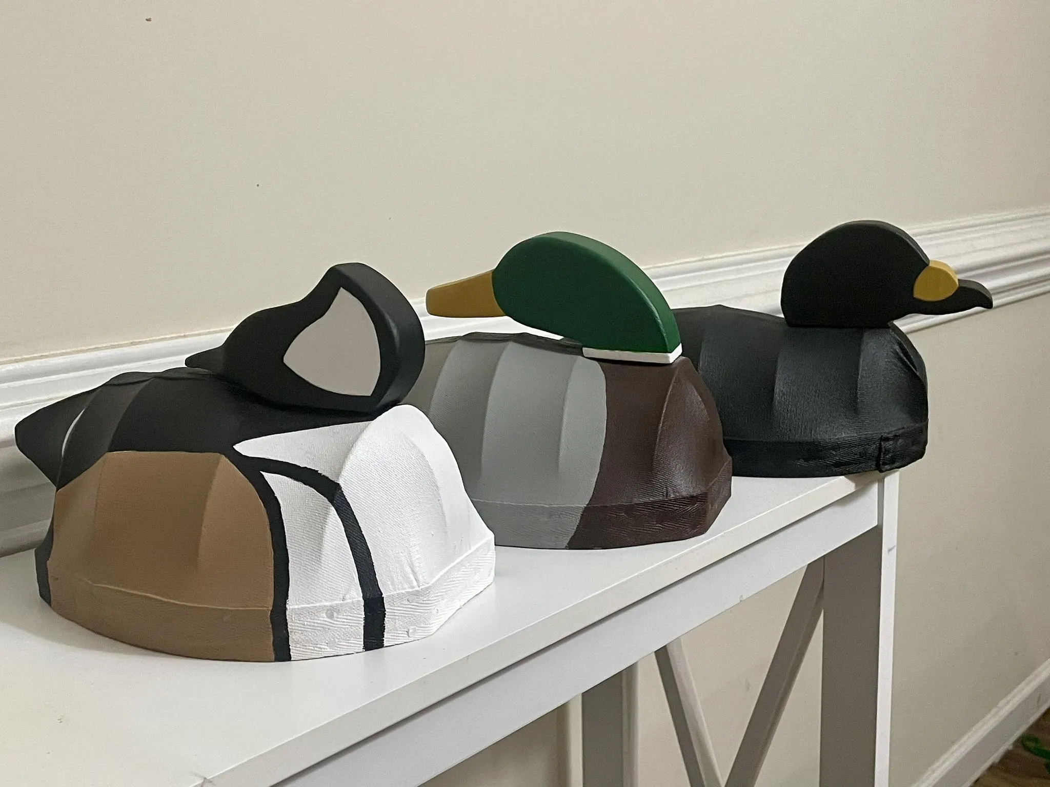 Three handmade waterfowl decoys displayed on a shelf.